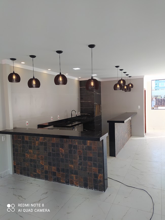 Ambiente interno com bancada de pedra e pendentes pretos